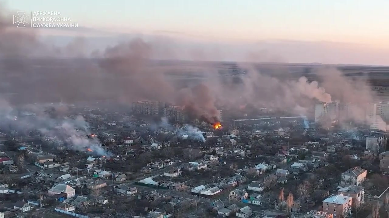 Ukrainian soldiers traversing a ruined, muddy battlefield near Bakhmut